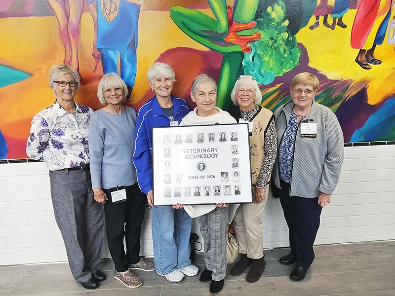 Six women pose together, holding a sign commemorating the Veterinary Technology Class of 1976.